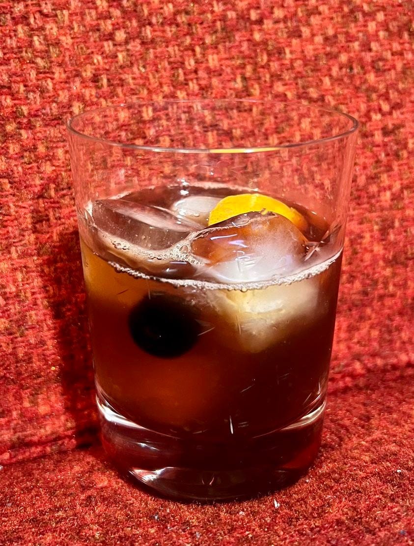 Image of a high-ball glass with a cocktail and some ice.