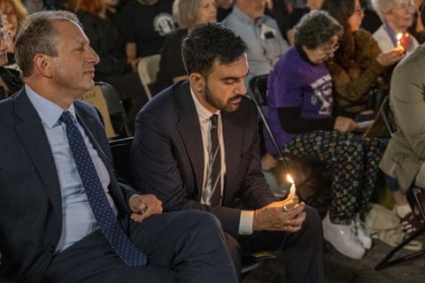 a man holding a candle with others seated next to him a man holding a candle with others seated next to him