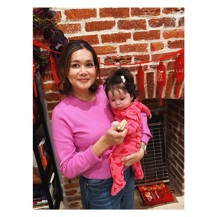 Woman smiling and carrying a baby. A platter filled with dumplings.