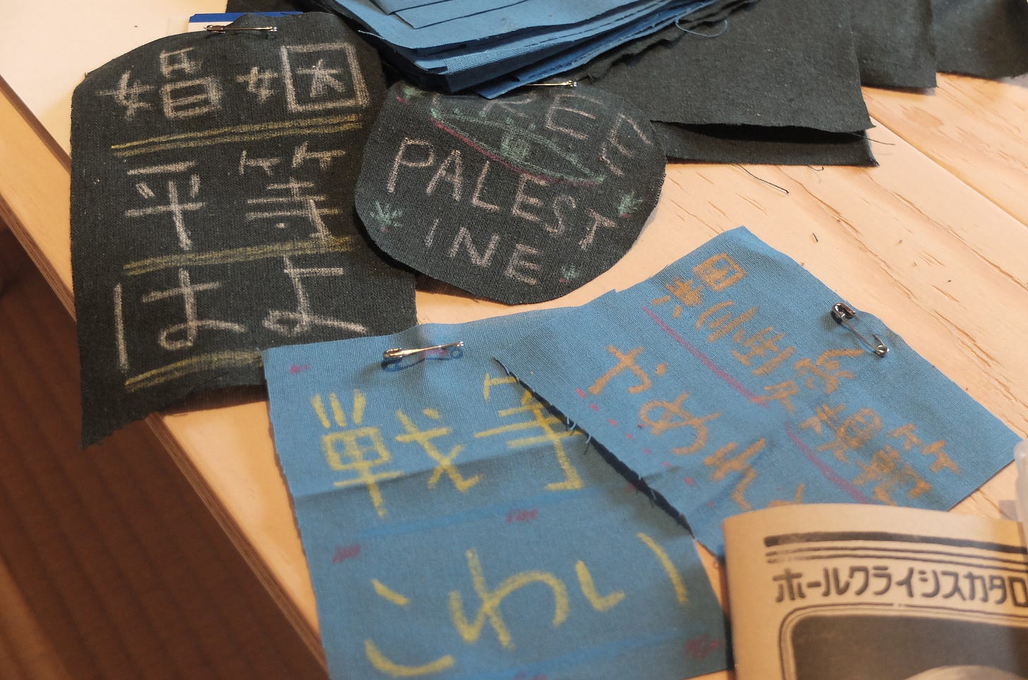 イベントの様子。木のテーブルの上に、制作されたパッチが置かれている。パッチには「戦争こわい」「婚姻平等はよ」「FREE PALESTINE」などが書かれている。