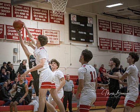 Five pictures of CVU boys basketball players in various stages of leaping and shooting with the ball. White uniforms with red lettering.