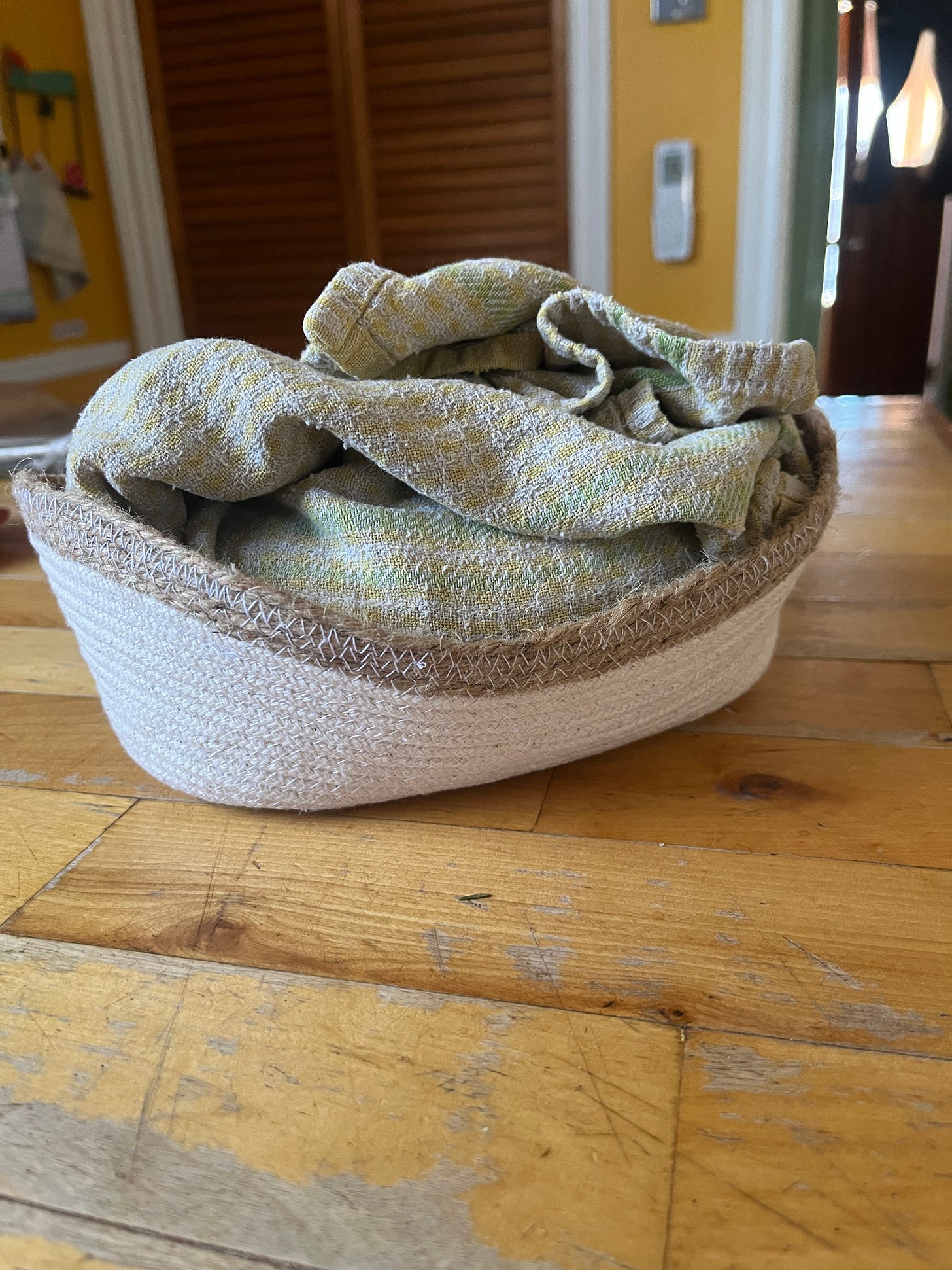 a small, oblong white basket with a mysterious mass inside wrapped up in a tea towel a small, oblong white basket with a mysterious mass inside wrapped up in a tea towel