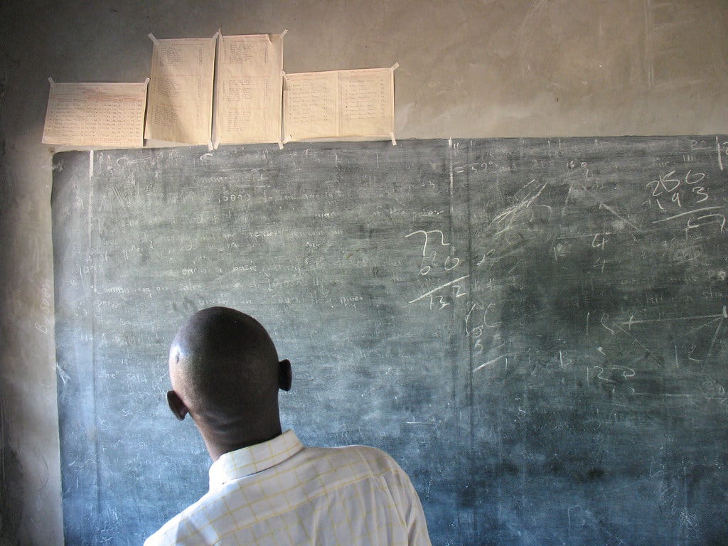 Back of someone's head as they read a dusty chalkboard. "Chalkboard" by aaron.knox is licensed under CC BY-NC-SA 2.0 