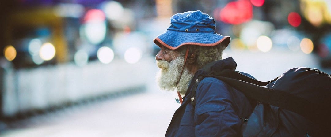 man in black jacket and blue knit cap standing on road during daytime