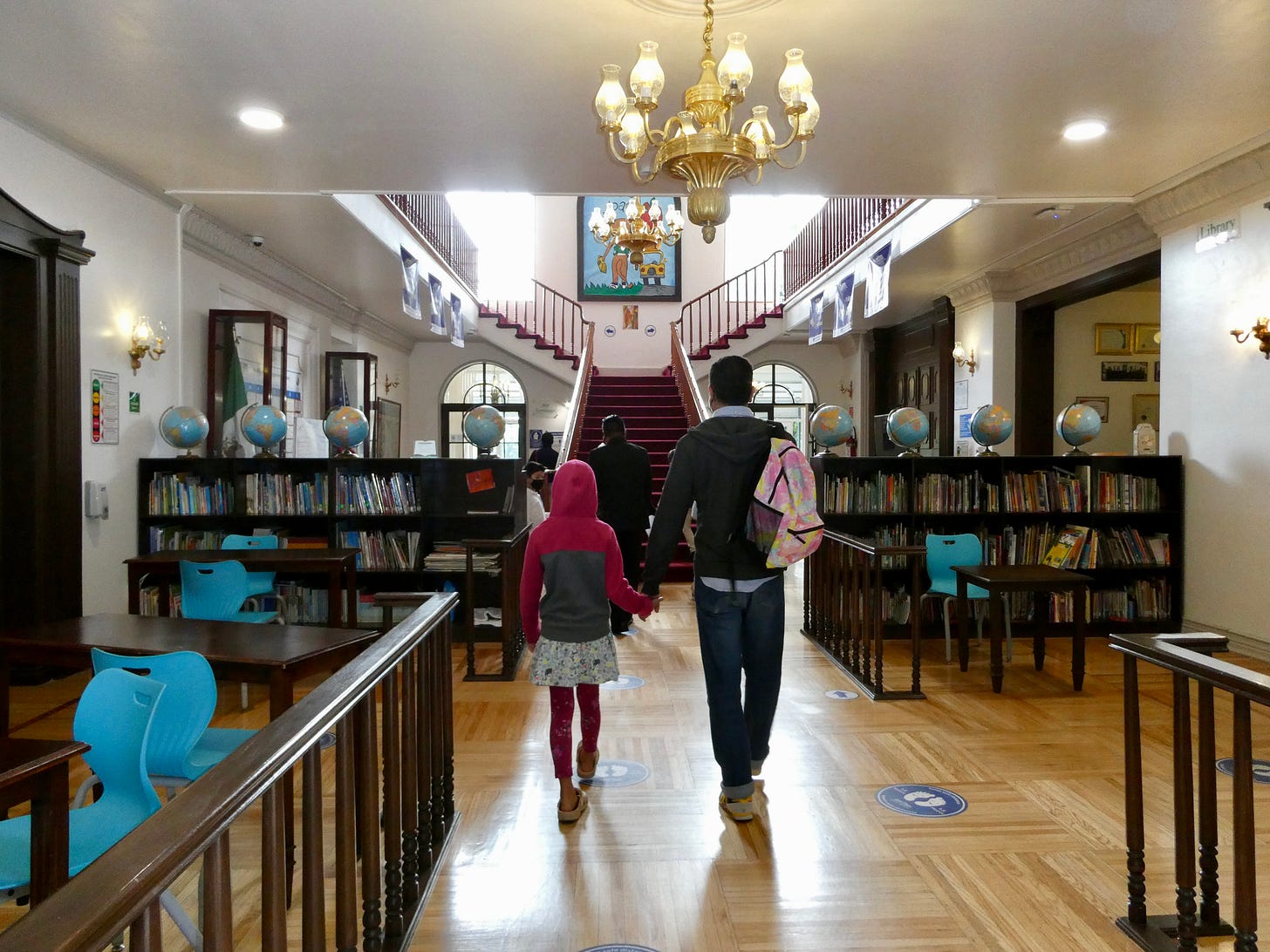 foyer of school lined with bookshelves facing staircase