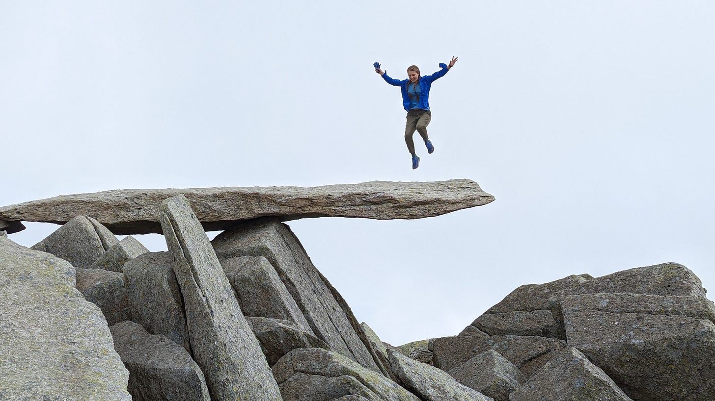 The author hovers mid-leap above a giant cantilevered rock