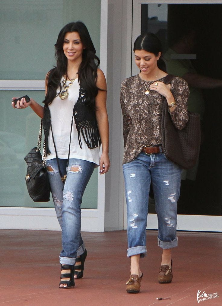 This may contain: two women walking down the street with cell phones