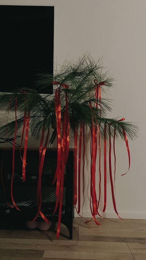 This may contain: two christmas trees with red ribbons hanging from them in front of a flat screen tv
