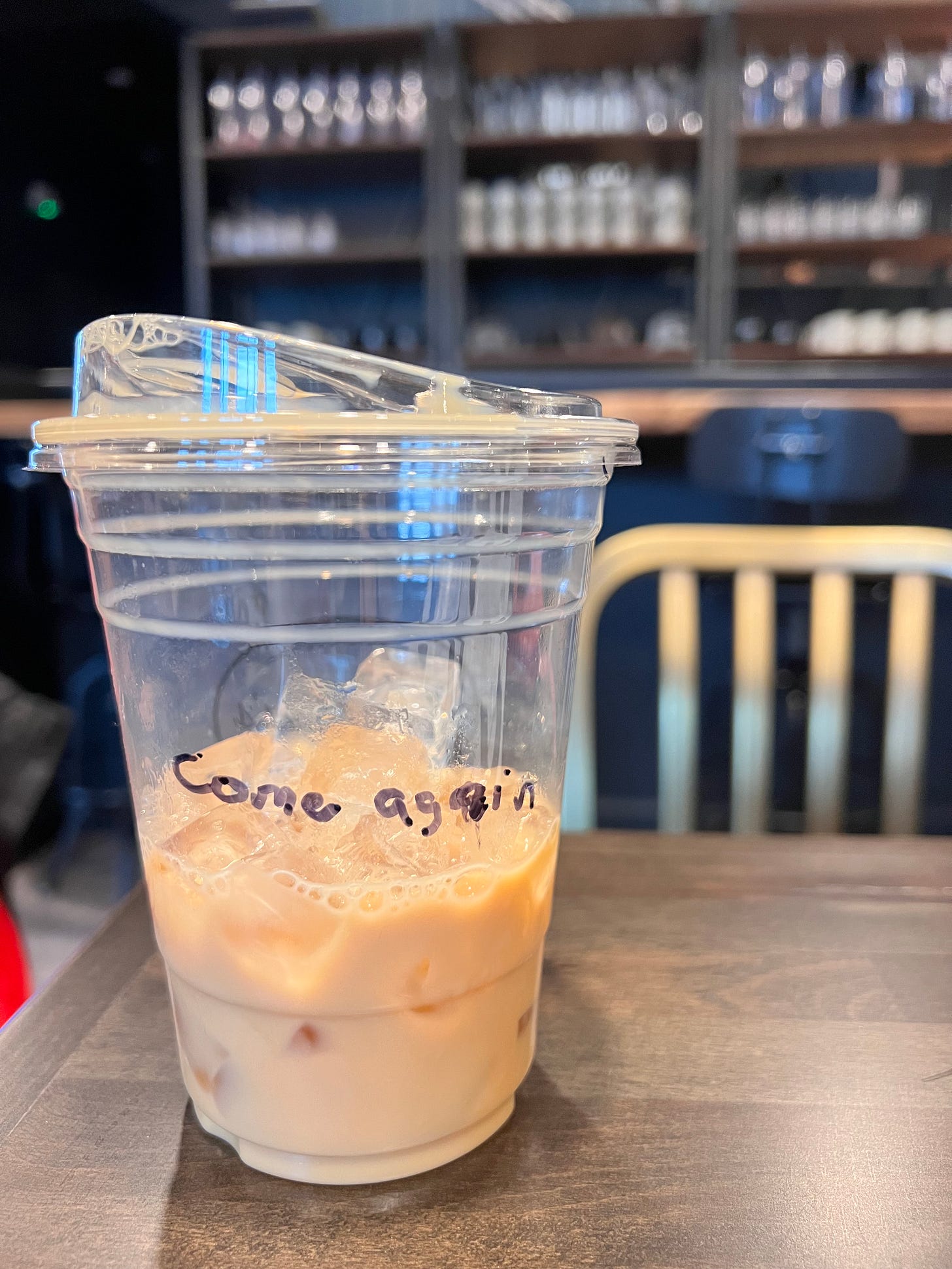 half an iced coffee in a plastic cup with a note that says "come again"