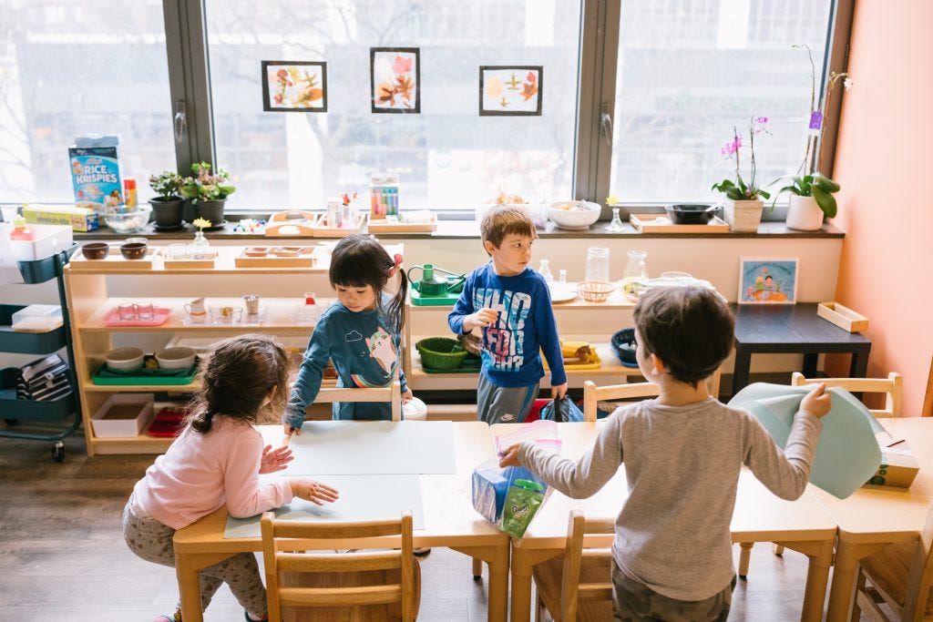 Young children working together in a Montessori classroom, setting up and cleaning a table as meaningful work rather than following a chore chart.