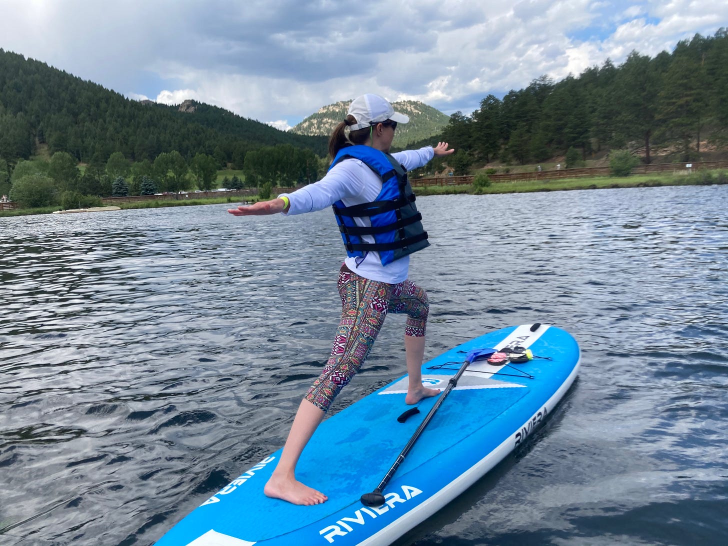 a woman in warrior 2 pose on a stand-up paddleboard on the lake a woman in warrior 2 pose on a stand-up paddleboard on the lake