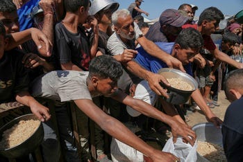 Palestinians struggle to get donated food at a community kitchen in Khan Younis, southern Gaza Strip