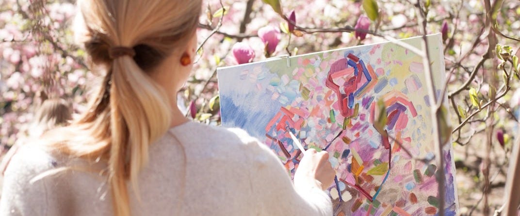 woman in white long sleeve shirt holding white and blue floral painting