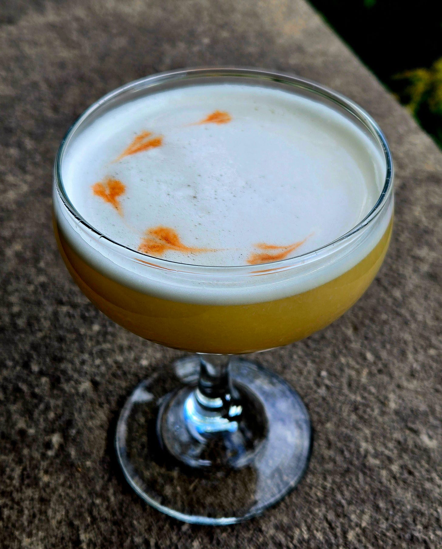 Sunset Beantown Bourbon in a Coupe with Angostura float atop a stone wall. Sunset Beantown Bourbon in a Coupe with Angostura float atop a stone wall.