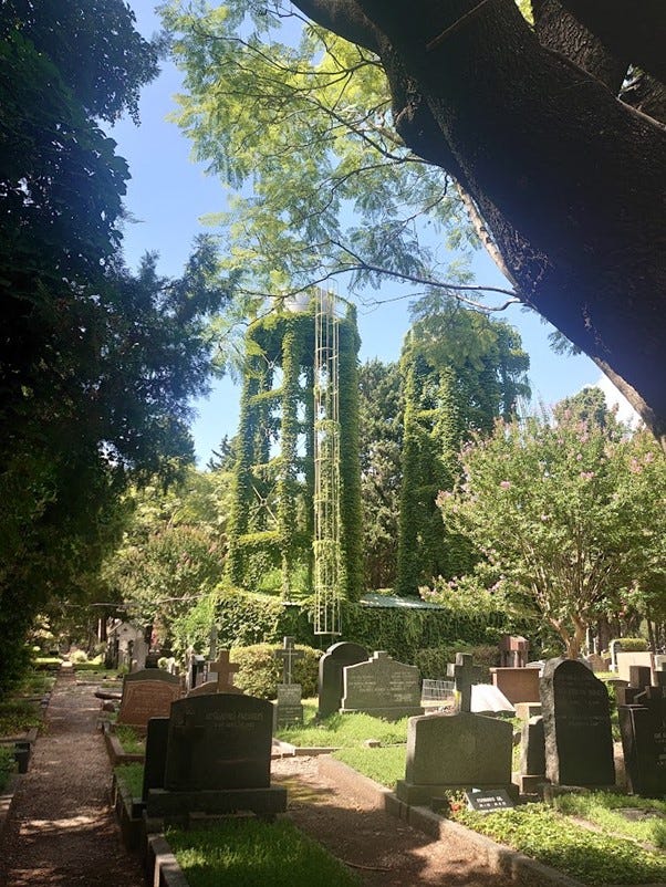 Chapel in a Cemetery surrounded by trees and greenery. A graveyard with a water tower covered in Ivy.