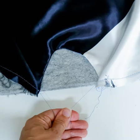 holding the bobbin threads to start gathering the edge of fabric holding the bobbin threads to start gathering the edge of fabric