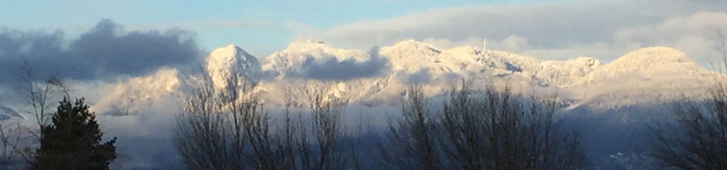 view of snow capped mountains peeking through clouds
