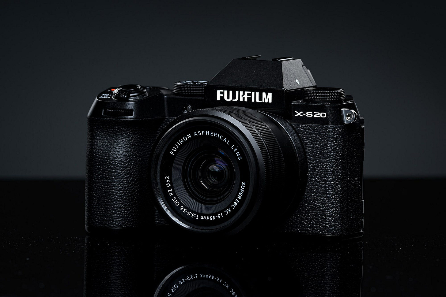 A black single-lens reflex digital camera by Fujifilm, sitting in a dark gray setting. A black single-lens reflex digital camera by Fujifilm, sitting in a dark gray setting.