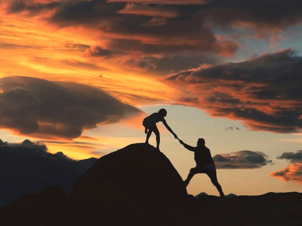 a couple of people holding hands on top of a hill