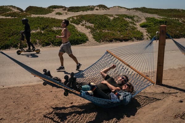 Ryan LaBerge lounges on a hammock with another person. A runner and someone on a scooter are seen on a nearby path.