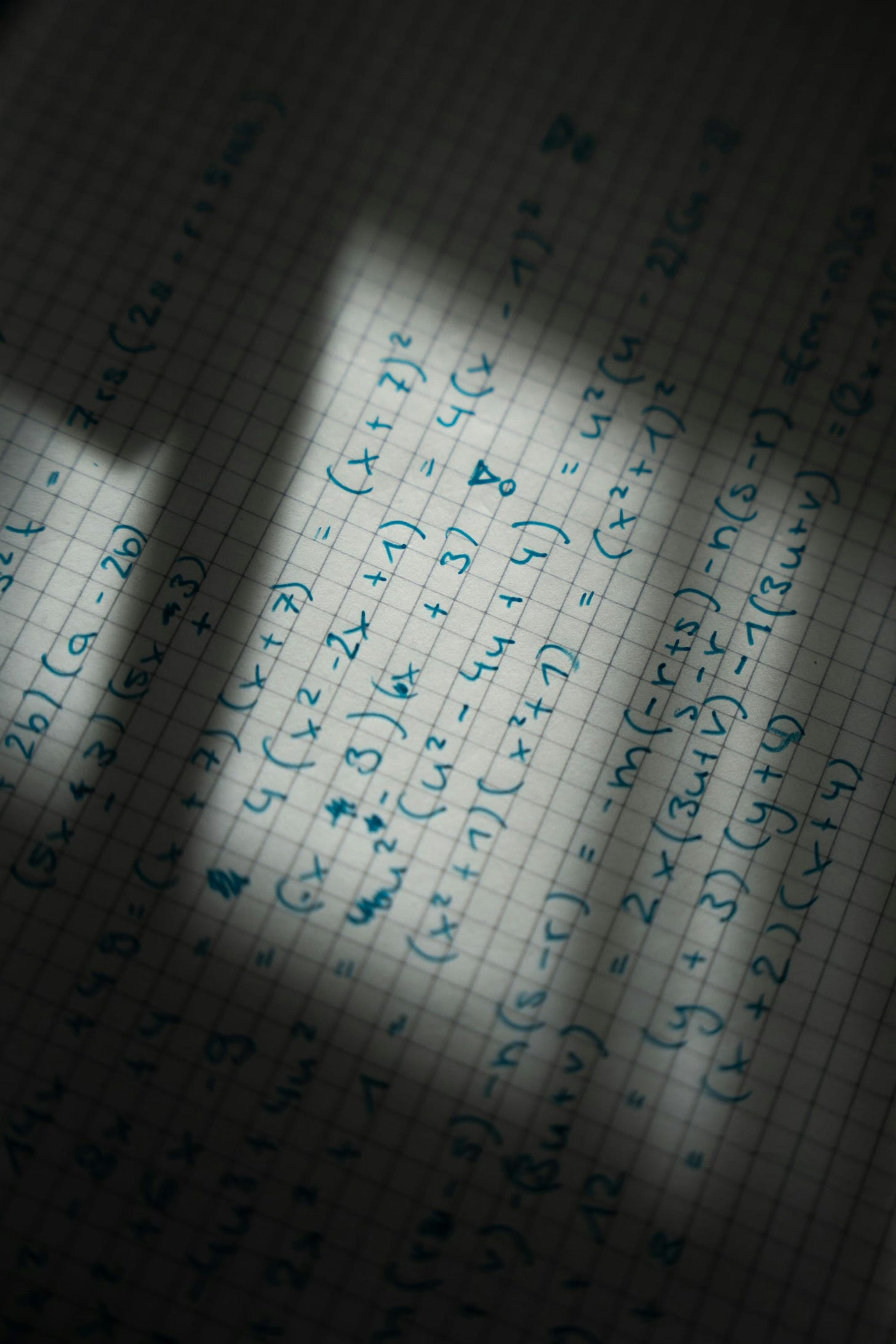 Graph paper with handwritten equations, seen in shadow Graph paper with handwritten equations, seen in shadow