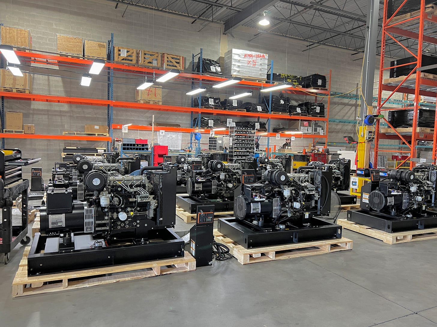 Aurora Generators warehoused on pallets.  Steel racking with sub-assemblies and components on shelves.