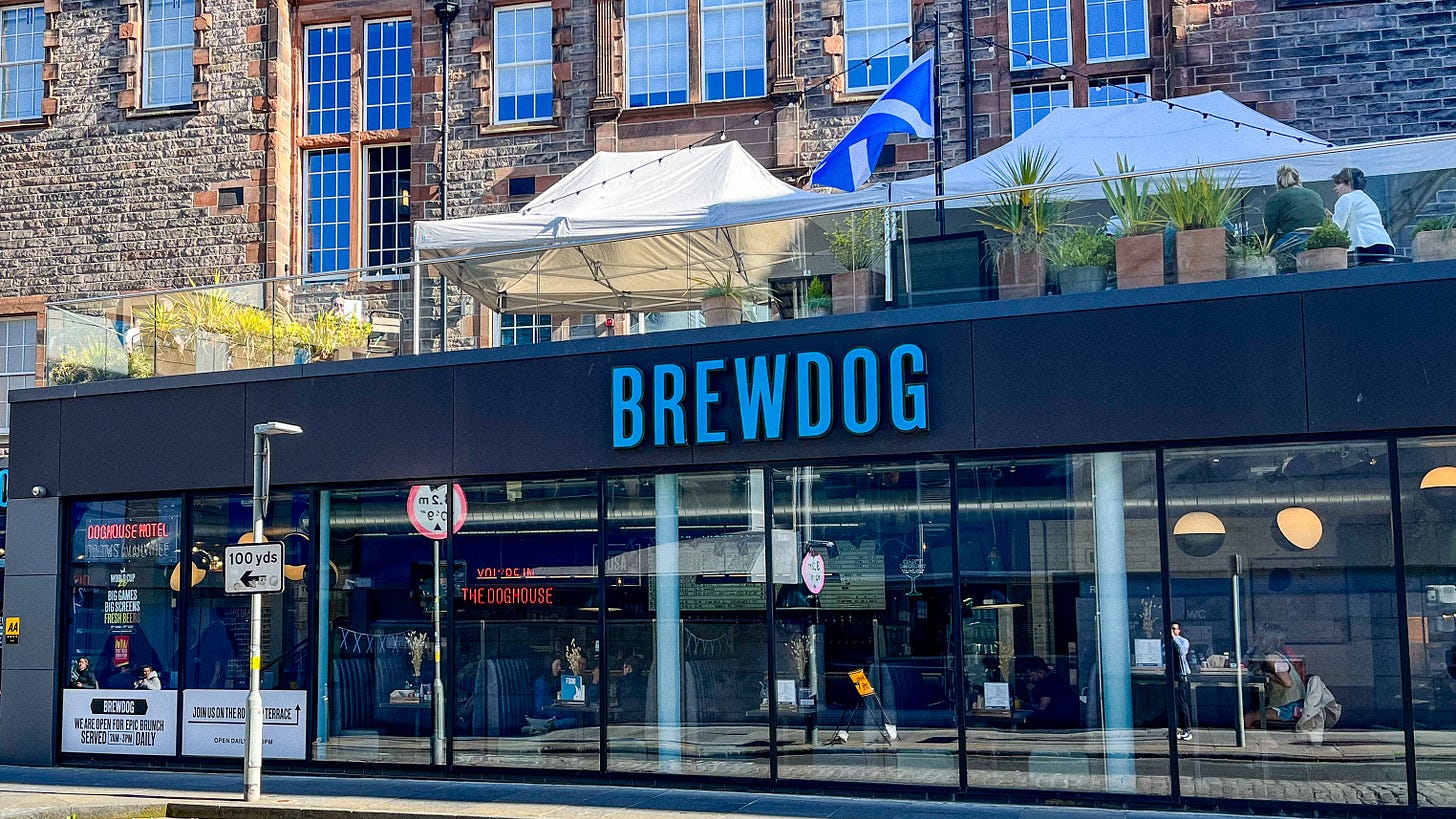 The exterior of the BrewDog DogHouse, with a light blue sign and a roof terrace above