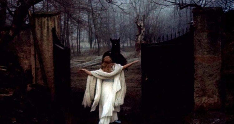 A woman in a white gown stands before a horse or beast in front of some open gates and a wintery forest.