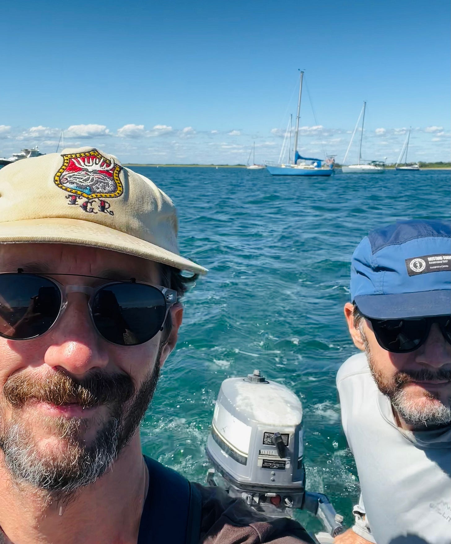 Author and husband in a dinghy with their sailboat behind them in Block Island
