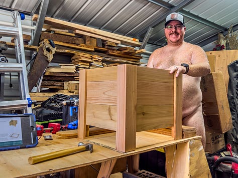 Author Dustin Cox is seen working completely nude in his wood shop. Cutting wood on a saw in the first image. Painting a wood frame black in the second image. Posing with a wood planter box that he built.