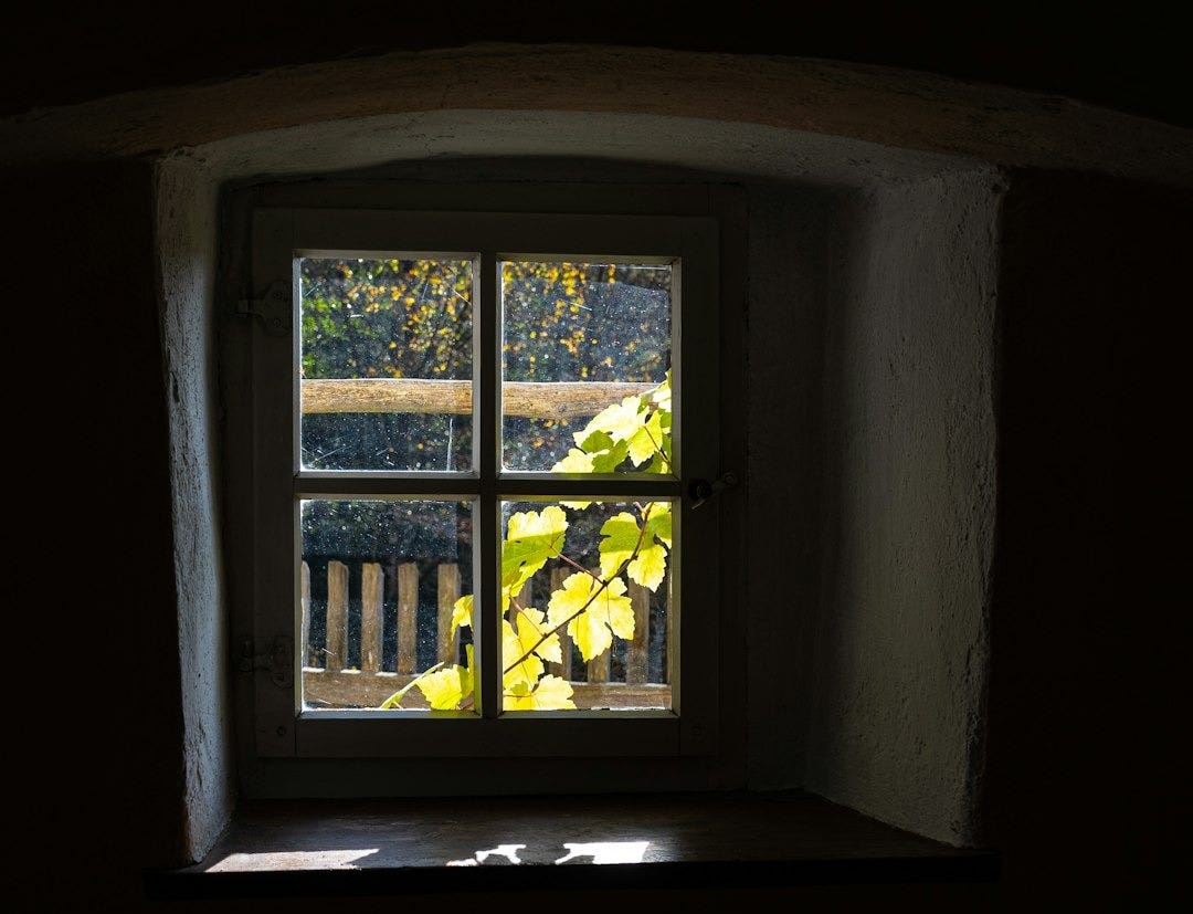 A window in a dark room with a fence outside A window in a dark room with a fence outside