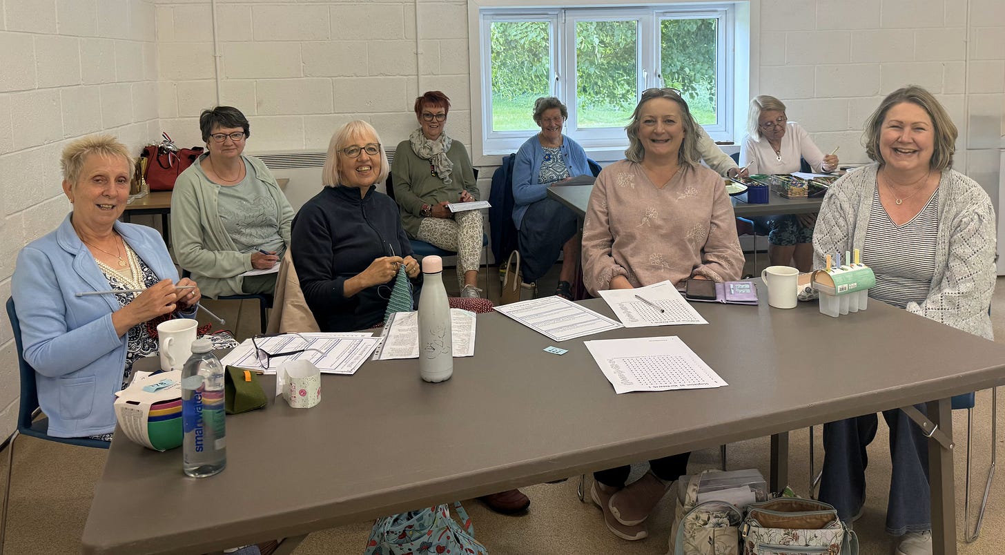A diverse group of women at a table, collaborating with papers and pens as they share ideas and notes.