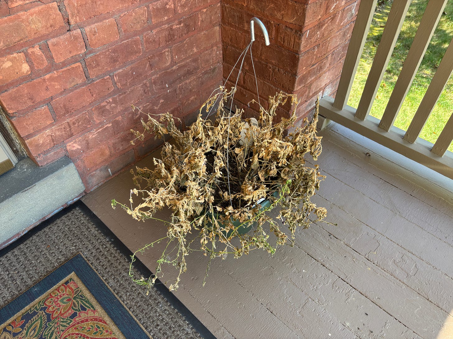 A basket of dead flowers sitting on a porch.