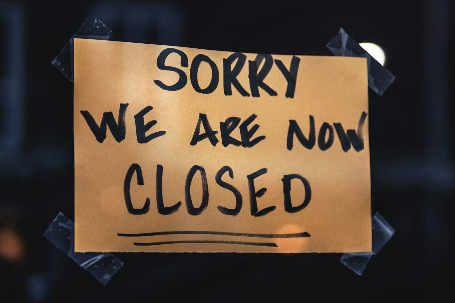 A brown sign with black writing, stating, "Sorry We Are CLOSED," on an unnamed business's door