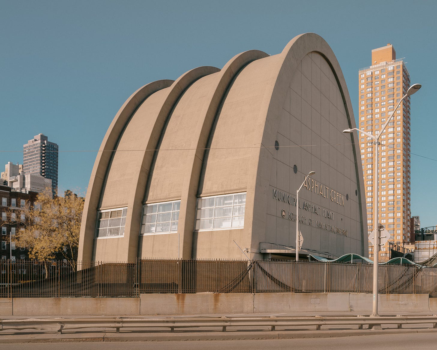 architectural color photo of a large concrete archway behind an empty road blue sky sunny day