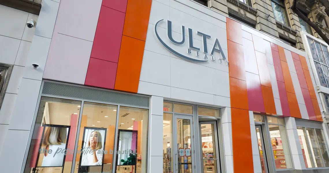 The modern storefront of an Ulta Beauty retail location featuring the iconic white, orange, and pink paneled exterior and Ulta logo above the entrance.