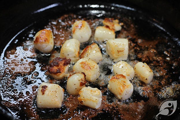 seared sea scallops cooking in a cast-iron pan