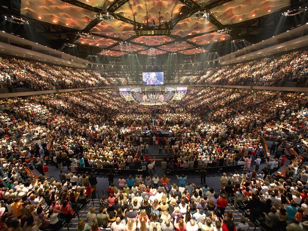 Large stadium-style auditorium filled with people facing toward a large screen