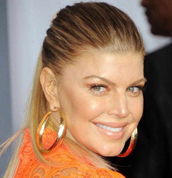 This may contain: a woman in an orange dress with large gold hoop earrings on her head and smiling at the camera This may contain: a woman in an orange dress with large gold hoop earrings on her head and smiling at the camera