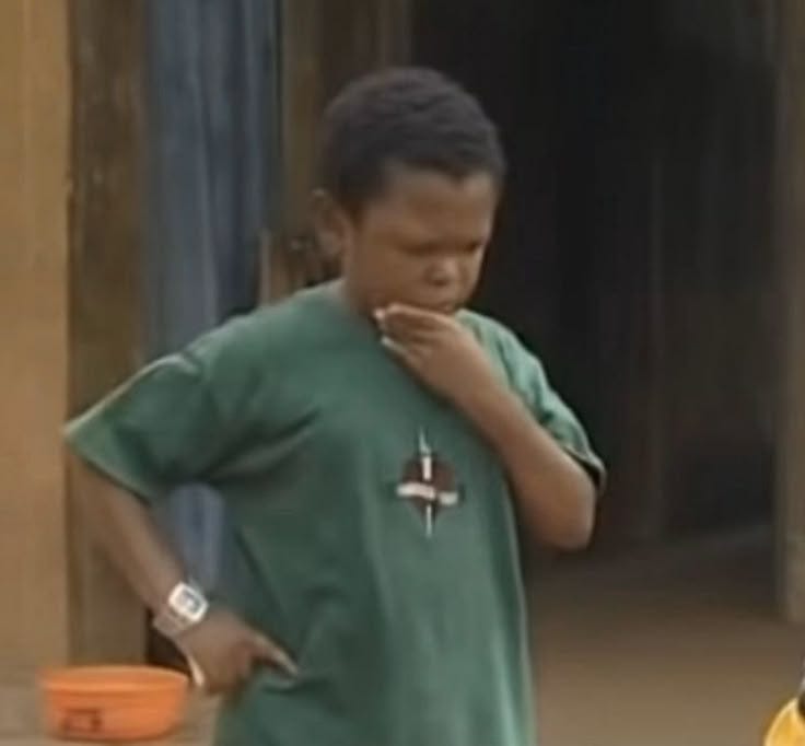 This may contain: a young man standing next to an orange bucket and wearing a green shirt with a cross on it