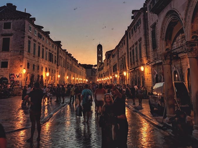 people standing between concrete buildings during golden hour