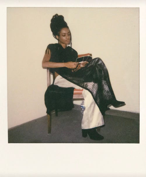 kendahl rose seated in a chair looking at polaroids