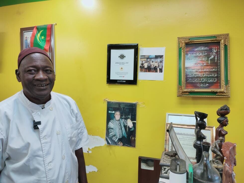 Abderrahmane Diop in his restaurant African Small Pot, posing next to a photo of his former deceased boss, an Italian chef. Abderrahmane Diop in his restaurant African Small Pot, posing next to a photo of his former deceased boss, an Italian chef.