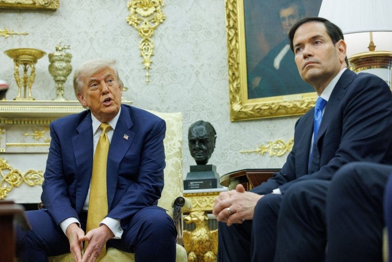 President Trump and Secretary of State Rubio sit side by side in the Oval Office, with its many gilt decor features prominent in the background President Trump and Secretary of State Rubio sit side by side in the Oval Office, with its many gilt decor features prominent in the background