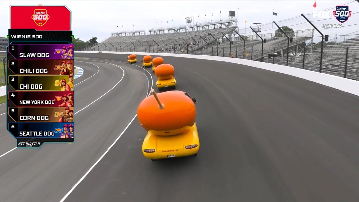 Wienermobiles all in a line, with Corn Dog in last place, heading around the Indy 500 track Wienermobiles all in a line, with Corn Dog in last place, heading around the Indy 500 track