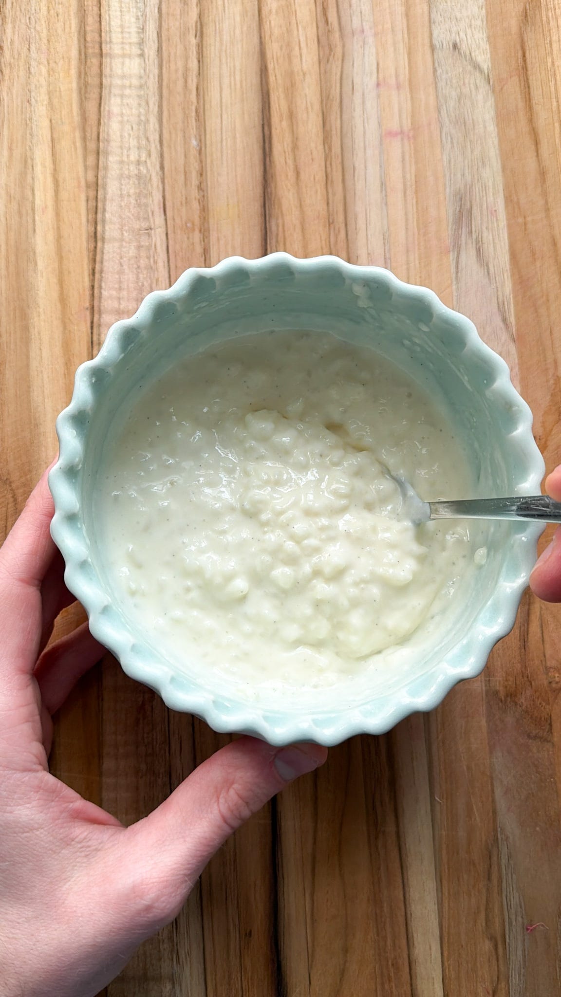 A photo of Martin scooping up a spoonful of rice pudding from a light blue bowl. A photo of Martin scooping up a spoonful of rice pudding from a light blue bowl.