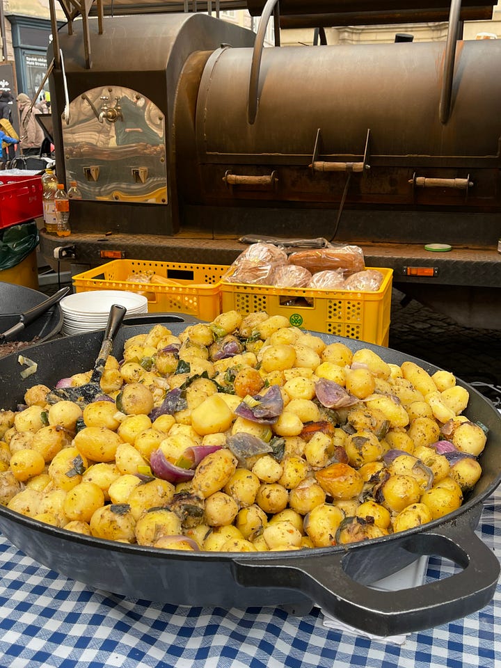 Classic Czech carnival fare — smoky sausages, golden potatoes, and roasted red peppers — the kind of hearty, unfussy food eaten standing up during Masopust celebrations.