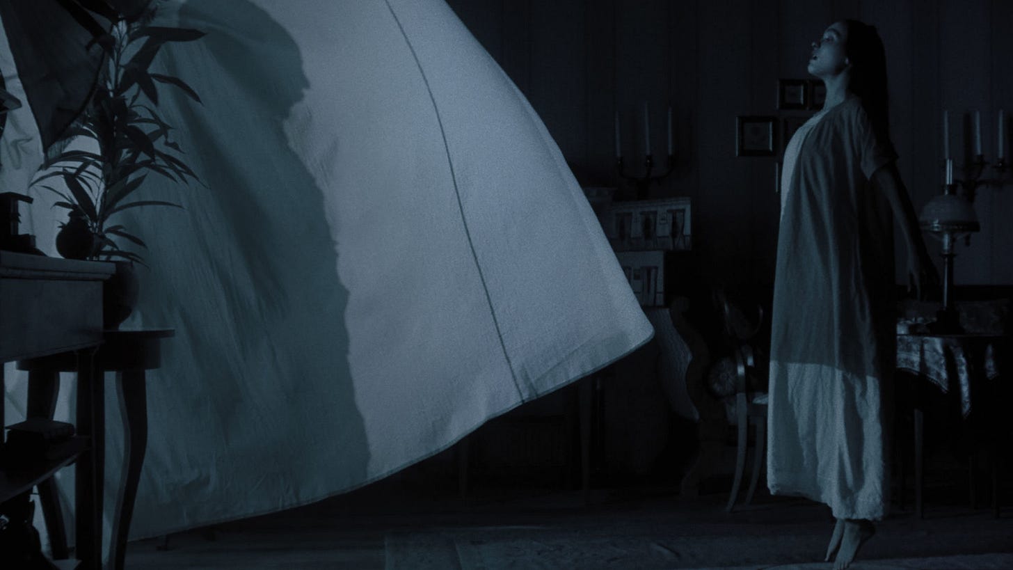 A still from the film. Lily-Rose Depp stands in front of a billowing curtain, marked with the shadow of a menacing figure.