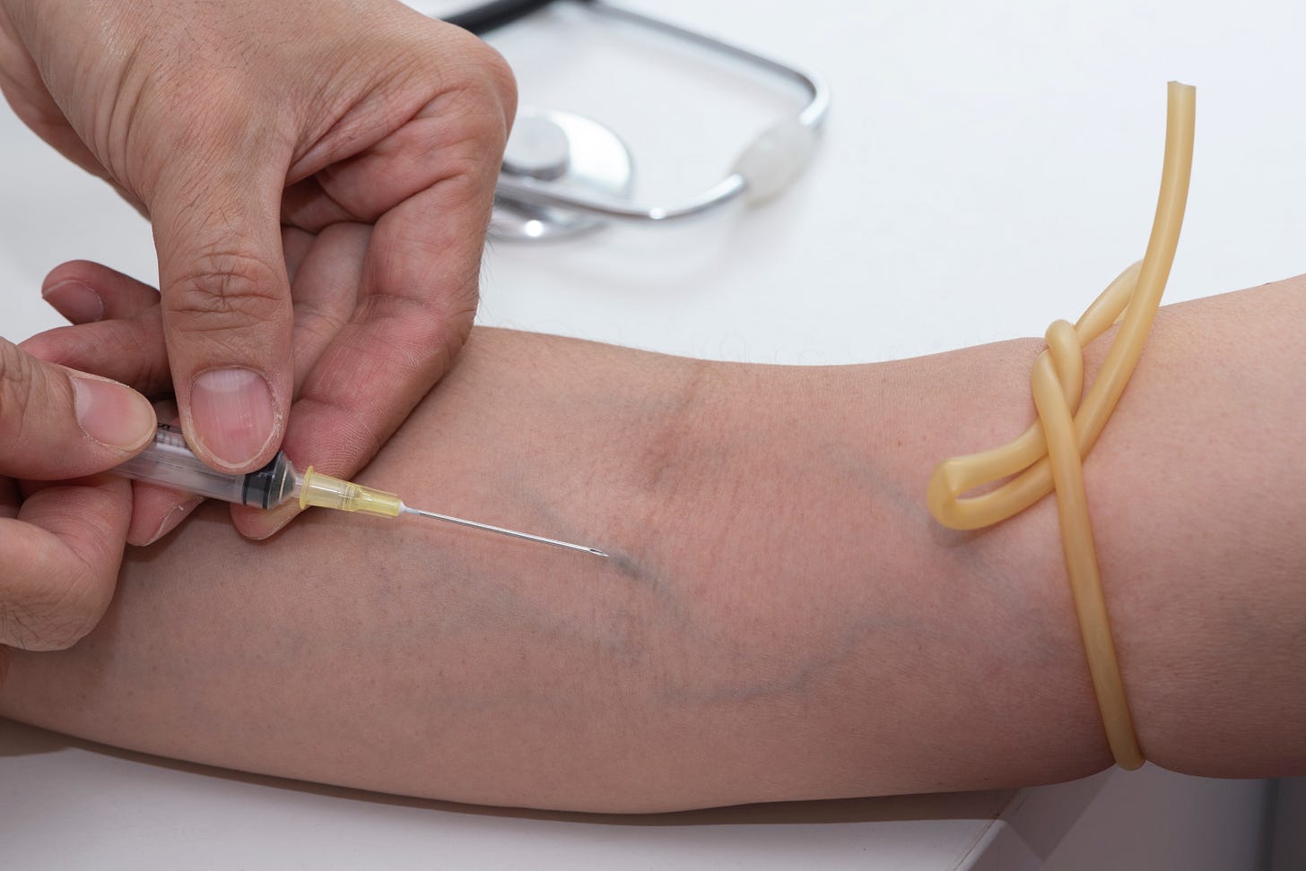 Someone with a rubber hose around their arm getting blood drawn. I think. I'm no phlebotomist. So much so I'm not even sure if that's the name for someone who  draws blood.