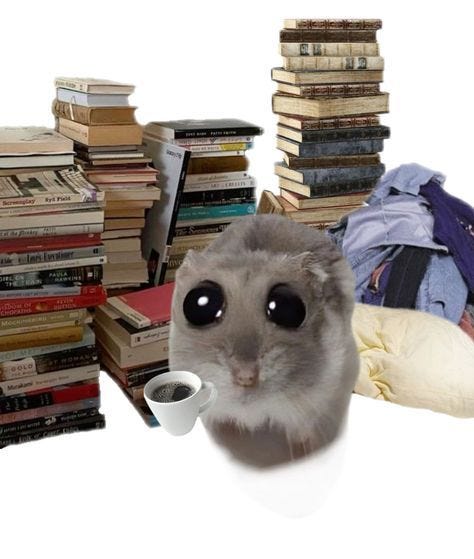This may contain: a hamster sitting in front of a pile of books and holding a coffee cup